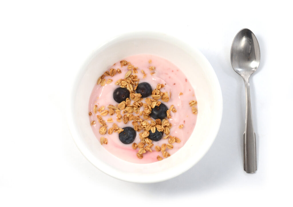 Bowl with yogurt, granola, and blueberries, with a spoon next to it