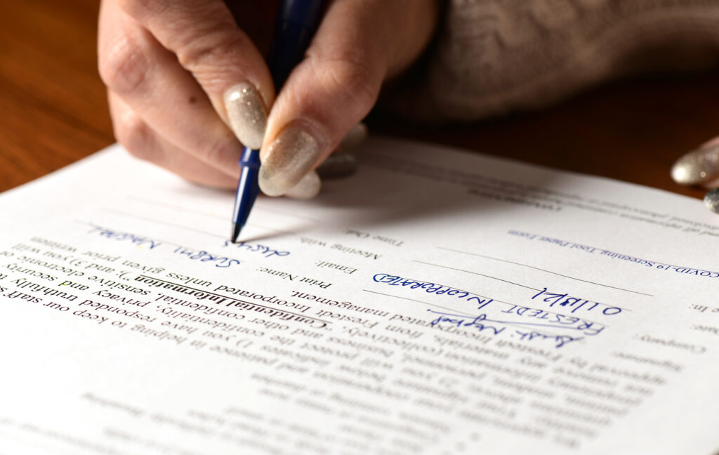 a hand holding a pen signing a document